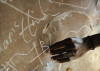 A schizophrenia patient writes on a blackboard near his home in Koidu, in eastern Sierra Leone. Switching effortlessly between his right and left hands, he covers the board in writings that are understood only by himself.