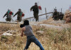 A Palestinian confronts a group of chraging Israeli Soldiers