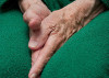 Old woman's hands tucked between her legs