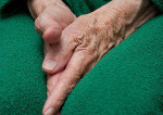 Old woman's hands tucked between her legs