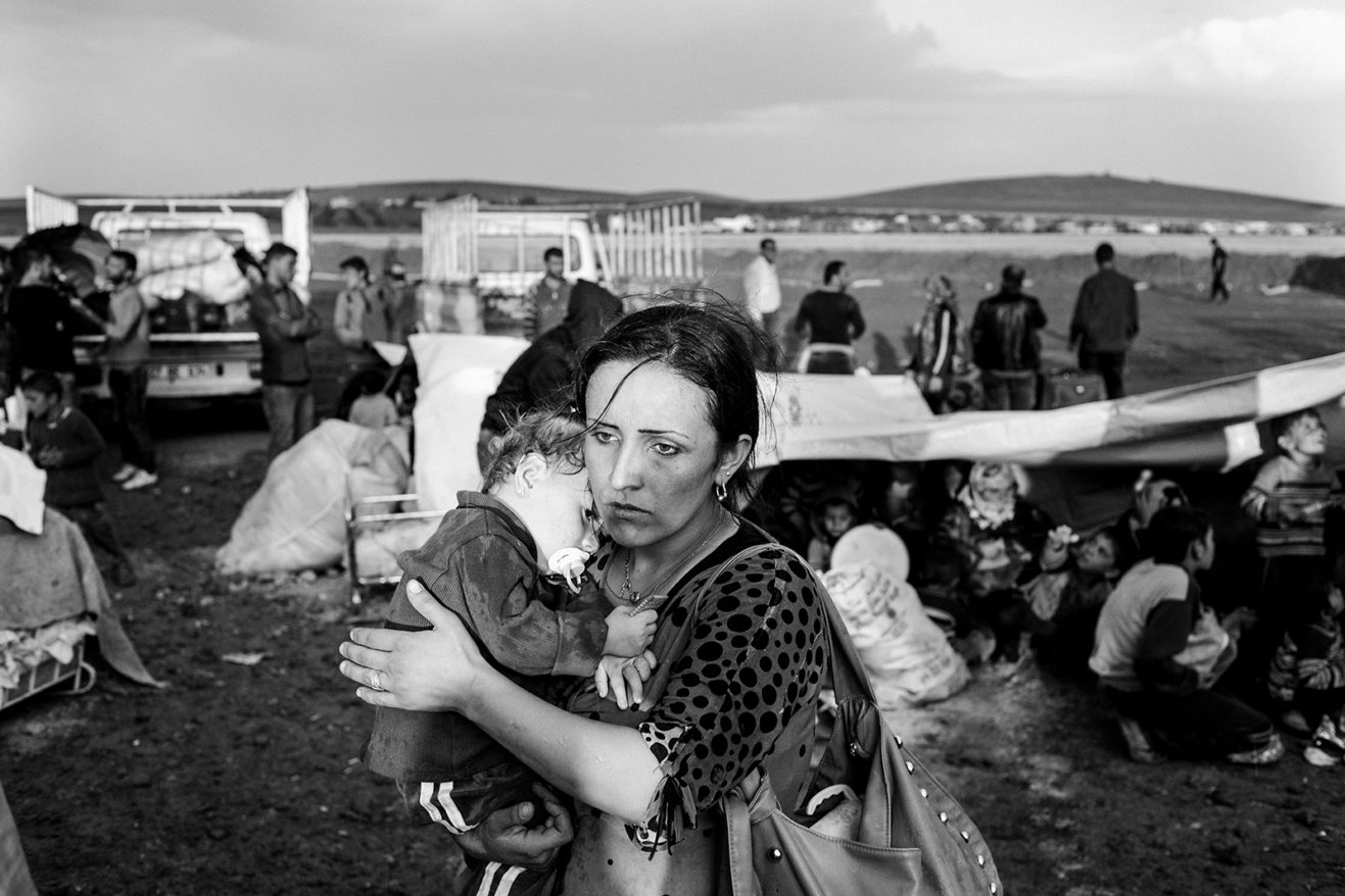 A woman crossing the border from northern Syria into Turkey with her son in her arms. October 2, 2014. Suruç, Şanlıurfa, Turkey.