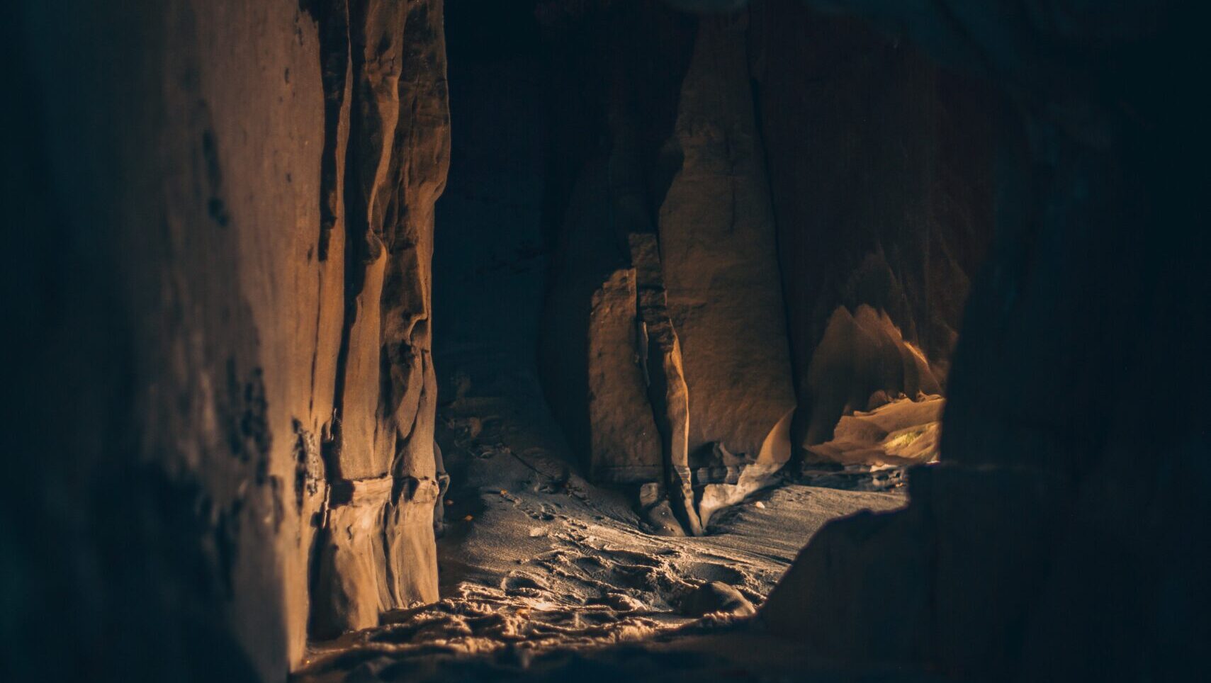 Image of the inside of a cave, sand on the ground.
